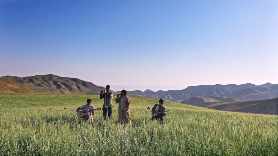 Still from SRS (Silk Road Songbook): musicians performing in a green valley below mountains
